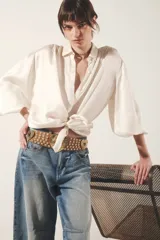 Camisa color blanco hueso de corte fluido, con cuello camisero, mangas largas abullonadas con puño abotonado y detalle de frunces.