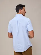Camisa de algodón blanca de manga corta, con cuello abotonado y botones frontales.
