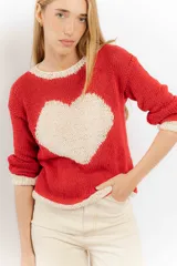 Sweater rojo tejido a mano con hilo, de corte holgado y cuello redondo. Presenta detalles en color crudo en el cuello, puños y ruedo.