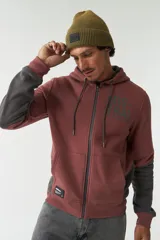 Campera de felpa color ladrillo con mangas grises, cierre frontal, capucha con cordones ajustables, bolsillos laterales con cierre, lettering estampado en el pecho y logo en grifa de goma en el lateral.