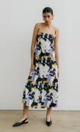 Vestido midi con estampado abstracto en tonos blanco, negro, azul y amarillo. Tiene breteles finos y abertura frontal.