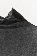 Top semitransparente tipo jersey confeccionado en hilatura de algodón 100%. Cuello alto y manga larga.