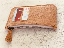 Billetera tarjetero de cuero con cierre y espacio para billetes y monedas.