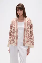 Chaqueta tipo kimono de tejido grueso color crema, con bordado floral en tonos rosados. Presenta un corte holgado y mangas anchas.
