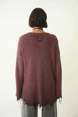 Sweater tejido color crudo, de manga larga con efecto desgastado y deshilachado en el ruedo y puños. Tiene cuello redondo y calce holgado.
