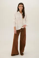 Pantalón de jean acampanado color caramelo con cintura alta y cinturón marrón con tachas.