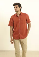 Camisa sport de manga corta color verde oliva, línea premium, con cuello clásico, cierre frontal con botones de coco y bolsillo de parche en el pecho. Confeccionada en lino y algodón.