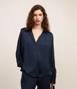 Camisa blanca de satén con cuello inglés, manga larga y cierre frontal con botones.