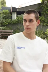 Remera blanca de algodón con estampado en la espalda con la frase "Follow the Waves" y dibujos de conchas marinas en color celeste.