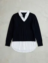 Buzo de hilado fino color beige con cuello y ruedo de gasa blanca que simula una camisa debajo. Presenta escote en V y mangas largas.