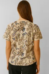 Remera de manga corta color marrón con estampado de flores en tonos beige y marrón oscuro, corte holgado y cuello redondo.