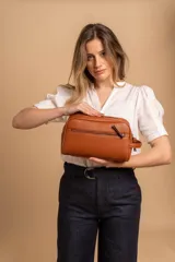 Neceser unisex color marrón de símil cuero, con doble compartimento superior y bolsillo frontal con cierre. Asa lateral para fácil transporte.