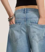 Bermuda femenina de jeans, modelo jorts, con trabillas en la cintura y bolsillos.