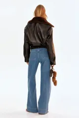 Pantalón de jean de algodón con leve stretch, tiro alto y pierna ancha. Presenta bolsillos de parche cuadrados en la parte delantera y bolsillos traseros. El lavado es celeste medio con efecto de desgaste vertical en las piernas.