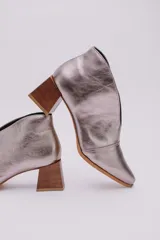 Botines color peltre de cuero con taco de madera y corte en V en el frente.