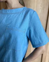 Remera negra con cuello redondo y mangas cortas, con detalle de pespuntes blancos en cuello, mangas, bolsillos frontales y ruedo.
