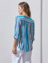 Blusa de gasa estampada con rayas verticales en tonos celeste, azul y blanco. Tiene cuello a la base con escote en V y abertura con botones. Las mangas largas son de largo regulable.