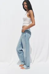Pantalón de jean celeste de tiro alto, corte recto y largo hasta el tobillo con dobladillo. Tiene cinco bolsillos y cierre frontal cruzado con cremallera y botón.
