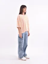 Remera de corte holgado con mangas cortas, a rayas horizontales blancas y naranjas.