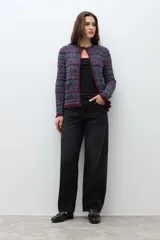 Chaqueta de tejido de punto con textura, diseño multicolor en tonos azul, rojo y blanco. Presenta cuello redondo, cierre frontal y detalles de flecos en los bordes y puños.