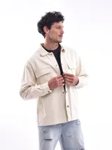 Campera gris oscuro de corte recto, con cuello clásico, cierre frontal con botones a presión, dos bolsillos de parche en el pecho con solapa y puños abotonados.