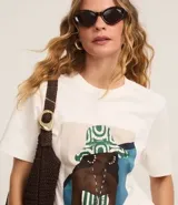 Remera blanca de algodón con estampa de una mujer con sombrero y traje de baño a rayas.
