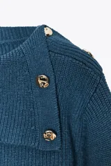 Sweater color crudo de tejido de punto acanalado, con cuello solapa abotonado y mangas largas abullonadas.