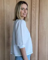 Remera blanca de algodón con mangas 3/4 abullonadas y cuello redondo. Presenta costuras a contratono en ruedo y cuello.