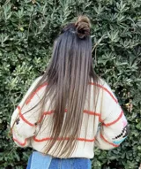 Sweater marrón tejido a mano con diseño de personas corriendo en colores rosa, celeste, blanco y amarillo. De corte holgado y cuello redondo.