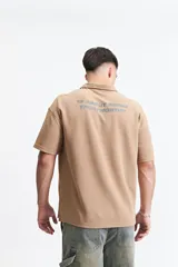 Polo azul marino con textura y corte oversize. Presenta un logo estampado en el pecho y mangas cortas.