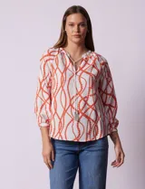 Blusa estampada blanca con diseño de cadenas y círculos color naranja. Cuello redondo con escote en V y lazo de ajuste. Manga 3/4.