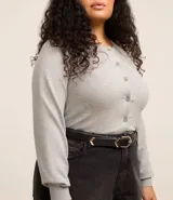 Cardigan gris de punto con cuello redondo, manga larga ajustada y bajo ajustado. Cierre frontal con botones.