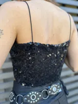 Top corto negro con lentejuelas y tirantes finos.