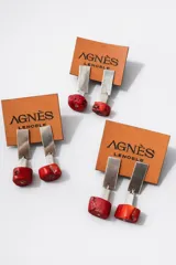 Aros colgantes con base rectangular de alpaca y una piedra irregular de color rojo en la parte inferior.