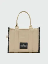 Bolso tote grande Marc Jacobs color beige con estampado del logo de la marca en negro. Tiene doble asa de mano y laterales con inscripción de la marca.