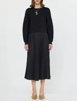 Conjunto de buzo y vestido negro marca Current Air. El vestido es de satén con escote en V y falda plisada. El buzo es de tejido calado, liviano y delicado.