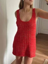 Vestido corto de tejido de punto en color rojo con hilos dorados (lurex) entretejidos, de corte recto y escote redondo. Presenta terminaciones en crochet en el ruedo y escote.