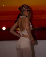 Pantalón largo de tejido ligero y traslúcido color beige claro, de corte acampanado.