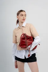 Cartera tipo bolso capitoneada de cuero color rojo, con asa de cadena plateada entrelazada con cuero. Forrada por dentro y con bolsillo interno.