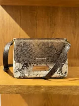 Cartera bandolera de cuero con estampado de piel de serpiente en tonos marrón y beige. Tiene correa larga ajustable y cierre con solapa.
