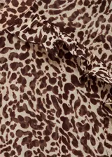 Vestido corto con estampado animal print de leopardo, cuello redondo, manga larga y detalles drapeados. Con forro interior y cierre de botón en la parte posterior.