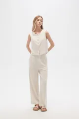 Pantalón de viscosa color beige, de corte ancho y tiro alto, con bolsillos laterales.
