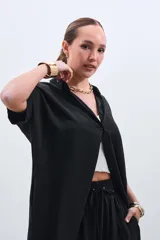 Camisola negra de tencel con cuello camisero, manga corta y cierre frontal con botones.