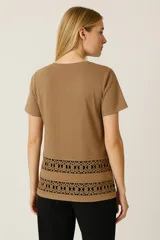 Remera color beige con cuello redondo y estampado con motivos geométricos en el ruedo.