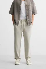 Pantalón color arena de corte recto, confeccionado en tejido de algodón y lino. Cuenta con cintura elástica ajustable con cordón, bolsillos delanteros y traseros de parche.