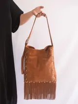 Bandolera de cuero color marrón con flecos y tachas plateadas. Tiene correa regulable, forro y bolsillo interior.