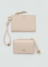 Monedero pequeño color beige con efecto piel y detalle de abalorios. Tiene cierre de solapa con botón magnético, bolsillo interior y bolsillo lateral con cierre de cremallera.