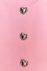 Top rosa de punto con cuello redondo y manga corta. Cierre frontal con botones en forma de corazón plateados.