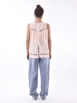 Blusa color durazno sin mangas, con cuello redondo y detalle de calado en la parte superior y en el ruedo.