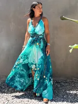 Vestido largo de tela fluida, color verde esmeralda con estampado abstracto en tonos turquesa y detalles dorados. Diseño asimétrico con un solo tirante tejido en el hombro.